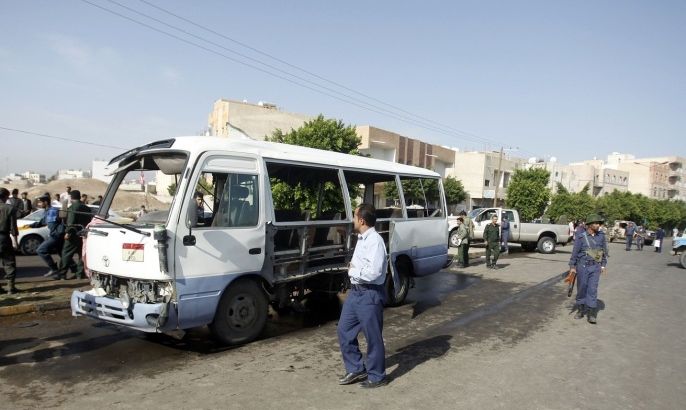 Air force troopers walk by a bus hit by a bomb attack in Sanaa August 25, 2013. At least six people were killed and 26 wounded on Sunday in the bomb attack on the bus carrying members of Yemen's air force to their base in the capital Sanaa, witnesses and medics said.