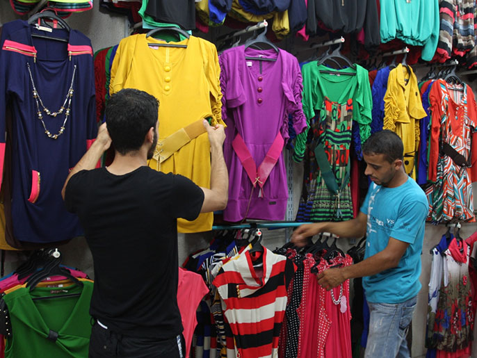 متسوقان في محل للملابس يتجهزان لموسم عيد الفطر بغزة (الجزيرة)