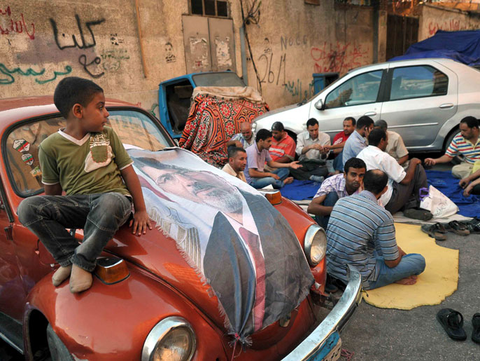طفل فضل الجلوس على ظهر سيارة تحمل صورة لمرسي بالإسكندرية (الفرنسية)