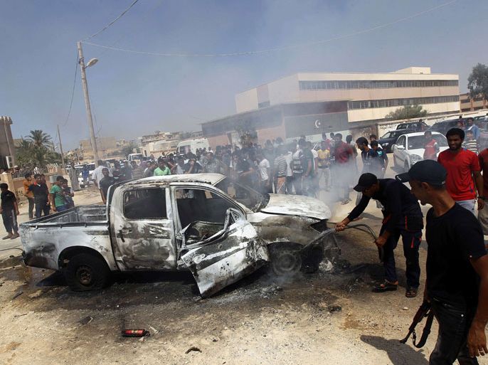 LIBYA : Benghazi residents and Libyan security forces gather around a burning car after an explosion killed the military prosecutor for Western Libya Youssef Ali al-Asseifar on August 29, 2013. Asseifar was probing several cases involving officials from the toppled regime of long-time dictator Moamer Kadhafi