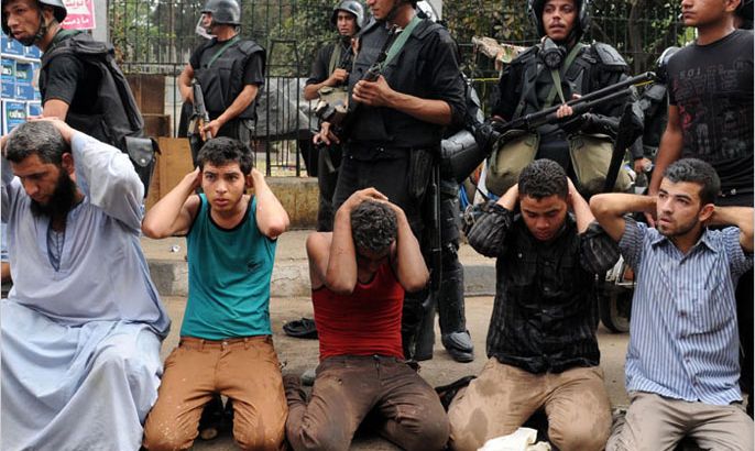 epa03824005 Egyptian security forces stand next to protesters arrested during the clearing of one of the two sit-ins of ousted president Morsi supporters, at Nahda square, near Cairo University, Cairo, Egypt, 14 August 2013