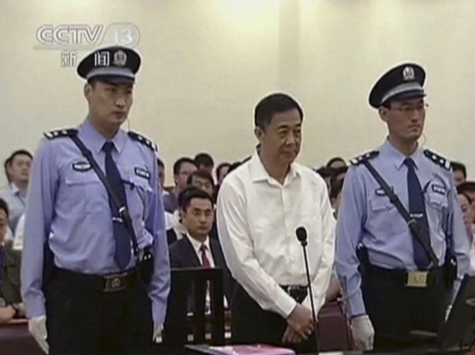 In this image taken from video, disgraced politician Bo Xilai, center, stands in the courtroom, flanked by police guards at Jinan Intermediate People's Court in eastern China's Shandong province on Thursday Aug. 22, 2013. Bo went on trial Thursday accused of abuse of power and netting more than $4 million in bribery and embezzlement, marking the ruling Communist Party's attempts to put to rest one of China's most lurid political scandals in decades. The superimposed words read: "Bo Xilai bribery, embezzlement and abuse of power trial begins" CHINA OUT, TV OUT.