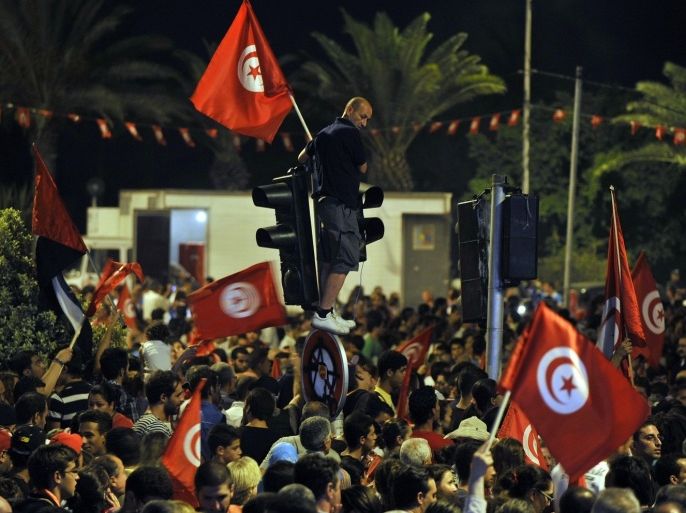 Tunisian poeple with flags chant slogans on August 4, 2013 in Tunis in front of the Constituent Assembly headquarters against Tunisia's Islamist government in Tunis. Tunisia said its forces killed a 'terror' suspect in a dawn raid Sunday and separately foiled a political assassination like the one that has plunged the country into crisis. The announcements came after rival protests for and against the Islamist-led coalition government, with the opposition demanding the resignation of the cabinet and the dissolution of the National Constituent Assembly.