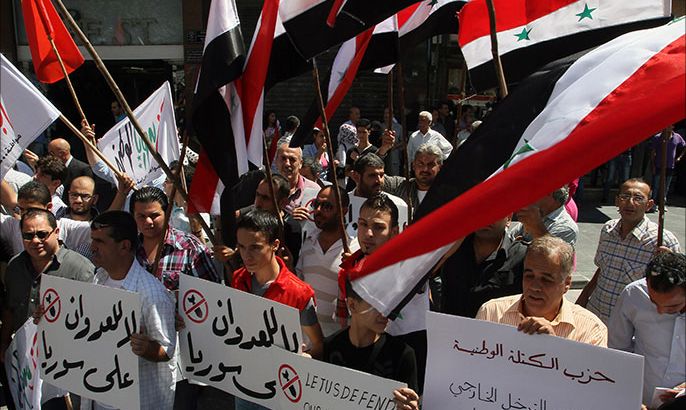 epa03859213 Syrian members of national parties and syndicates hold up national flags and banners during a sit in held at Youssef al-Azmeh Square in Damascus, Syria, 09 September 2013. Hundreds of Syrians gathered to protest against the US threats to launch a military strike against Syria. Assad said in an interview the US does not have evidence of a chemical weapons attack in Syria. EPA/STR