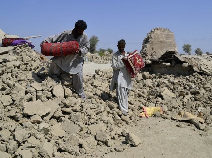 Survivors of an earthquake collect their belongings near the rubble of a mud house after it collapsed following the quake in the town of Awaran, southwestern Pakistani province of Baluchistan, September 25, 2013. The death toll from a powerful earthquake in southwest Pakistan rose to 327 on Wednesday after hundreds of mud houses collapsed on residents throughout the remote and thinly populated area, local officials said.