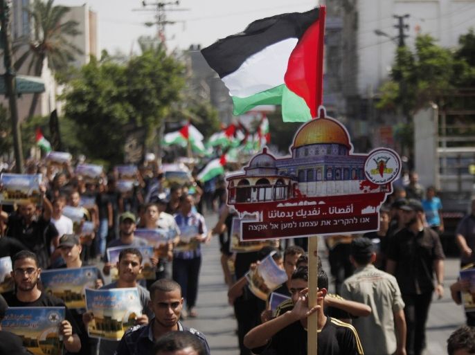 Palestinians from Islamic Jihad chant slogans and wave national flags during a rally in Gaza City, Friday, Sept. 13, 2013. Arabic on the placard reads, "We defend al-Aqsa mosque by our blood." The rally was organized to oppose Zionism and Israel's control of Jerusalem.