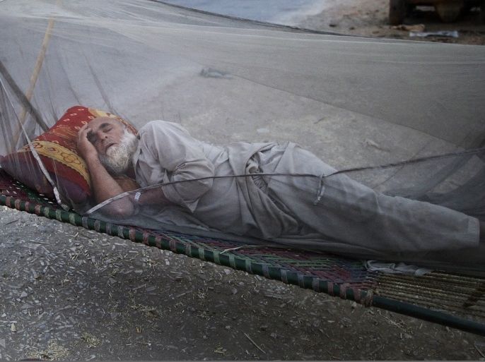 An elderly Pakistani man, who fled his home with his family from Pakistan's tribal areas, due to fighting between the Taliban and the army, sleeps on a bed covered with a mosquito net, on a roadside, on the outskirts of Islamabad, Pakistan, early Monday, May 20, 2013. As temperatures rise, many Pakistanis are sleeping outdoors to escape the heat trapped in their homes.