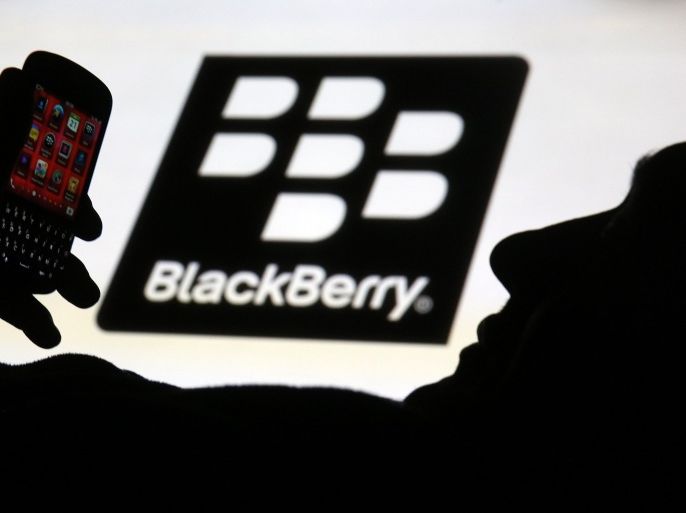 A man is silhouetted against a video screen with the Blackberry logo as he pose with a Blackberry Q10 in this photo illustration taken in the central Bosnian town of Zenica, September 21, 2013. BlackBerry Ltd warned on Friday it expects to report a huge quarterly operating loss next week and that it will cut more than a third of its global workforce, rekindling fears of the company's demise and sending its shares into a tailspin. The company, which has struggled to claw back market share from the likes of Apple Inc's iPhone and Samsung Electronics Co Ltd's Galaxy phones, said it expects to report a net operating loss of between $950 million and $995 million in the quarter ended Aug. 31, due to writedowns and other factors.