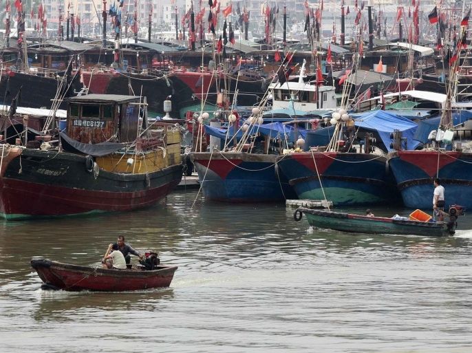 Fishermen drive a boat next to fishing ships docked at a port to shelter from Typhoon Wutip in Sanya, Hainan province September 29, 2013. China's maritime authority on Monday issued a yellow wave warning as Typhoon Wutip, the 21st of the season, approaches, Xinhua News Agency reported. China has a four-tier color-coded weather warning system, with red representing the most severe weather, followed by orange, yellow and blue. Picture taken September 29, 2013.