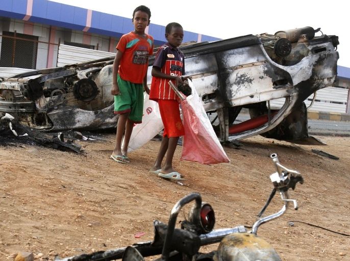 Sudanese boys walk amid burned vehicles after rioters torched a fuel station in Khartoum, Sudan, Thursday, Sept. 26, 2013. Sudanese authorities have deployed troops around vital installations and gas stations in Khartoum following days of deadly rioting over gas price hikes.