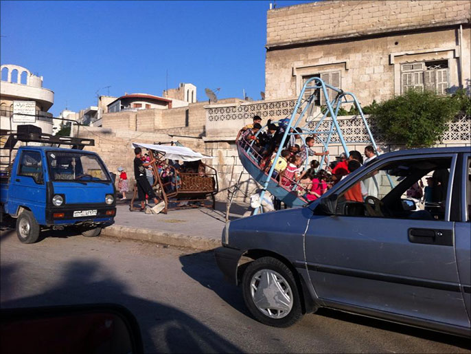 ‪أطفال يعتلون أرجوحة بأحد شوارع مدينة حماه‬ (الجزيرة)