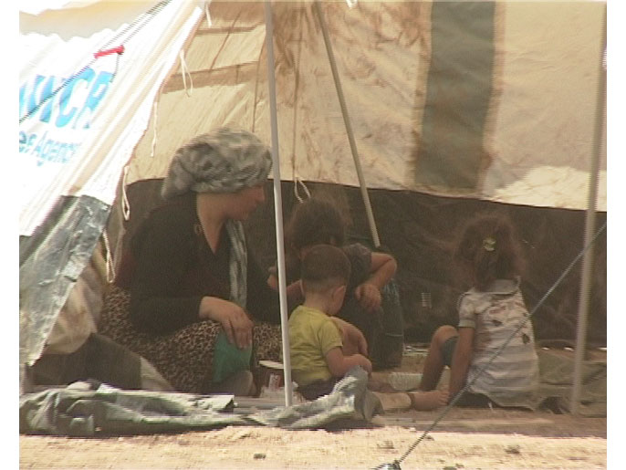 لاجئة سورية مع أطفالها داخل المخيم (الجزيرة نت)