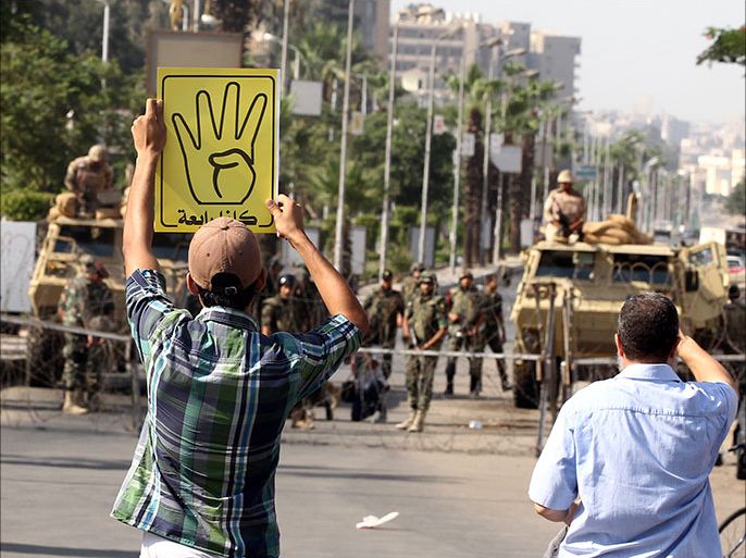 epa03866049 An Egyptian supporter of ousted President Mohamed Morsi holds a poster of the 'four-fingered salute' during a protest in front of Egyptian army soldiers near Rabaa Adawiya mosque in Cairo, Egypt, 13 September 2013. Morsi's Muslim Brotherhood has condemned his toppling as a coup and vowed to continue protests until he is restored to power. The so-called 'four-fingered salute' has come to symbolize the lives lost during the dispersal of the Rabaa al-Adawiya protest camp. EPA/KHALED ELFIQI