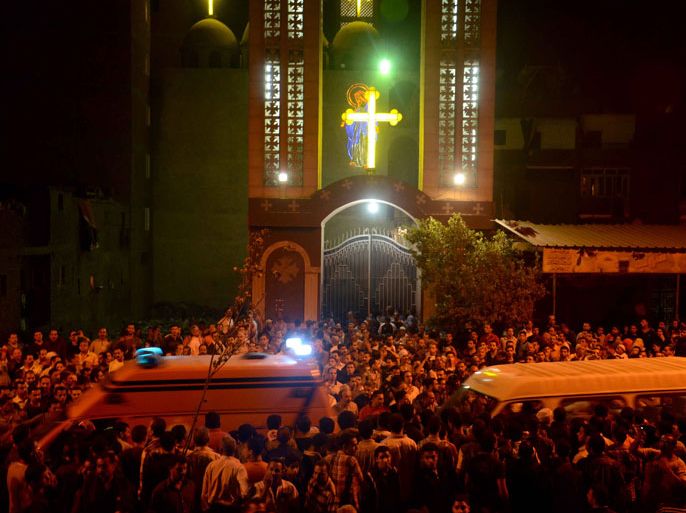 EGYPT : Ambulances drive through the crowd in front of the Virgin Mary Coptic Christian church in Cairo after gunmen on a motorbike shot dead three people late on October 20, 2013, including an eight-year-old girl, in a shooting attack on a group standing outside the church in the Egyptian capital's Al-Warak neighbourhood following a wedding ceremony. A health ministry official confirmed three people had been killed but said 12 people had in fact been wounded in the first such assault targeting Christians in Cairo since the military coup that ousted Islamist president Mohamed Morsi on July 3. AFP PHOTO / STR