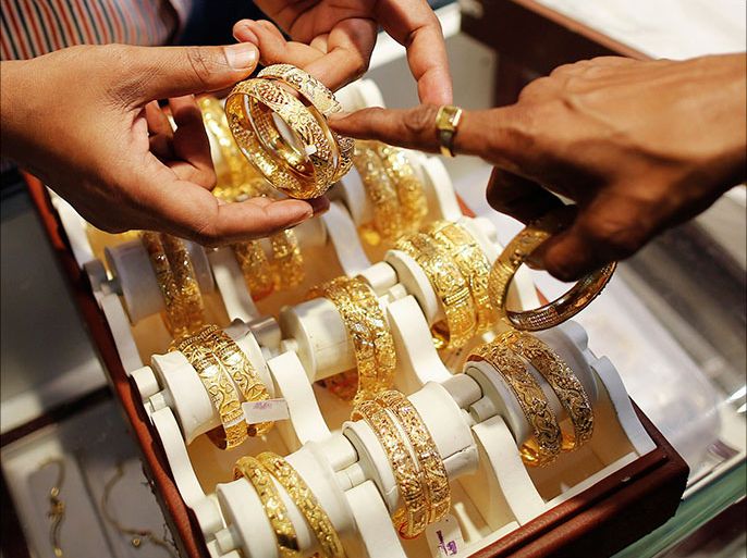 An employee shows gold bangles to a customer at a jewellery showroom on the occasion of Dhanteras, a Hindu festival associated with Lakshmi, the goddess of wealth, at a market in Mumbai November 1, 2013. A scarcity of gold and high