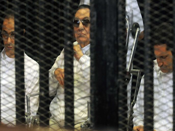 Former Egyptian president Hosni Mubarak (C) and his two sons Alaa (R) and Gamal (L) sit behind the bars of a cage inside the court room during their trial at the Police Academy in Cairo, Egypt, 25 August 2013. Mubarak was back in court on 25 August for a retrial over alleged complicity in the killing of protesters, four days following his release from prison after settling a corruption case. The trial was again adjourned till 14 September. EPA/STR
