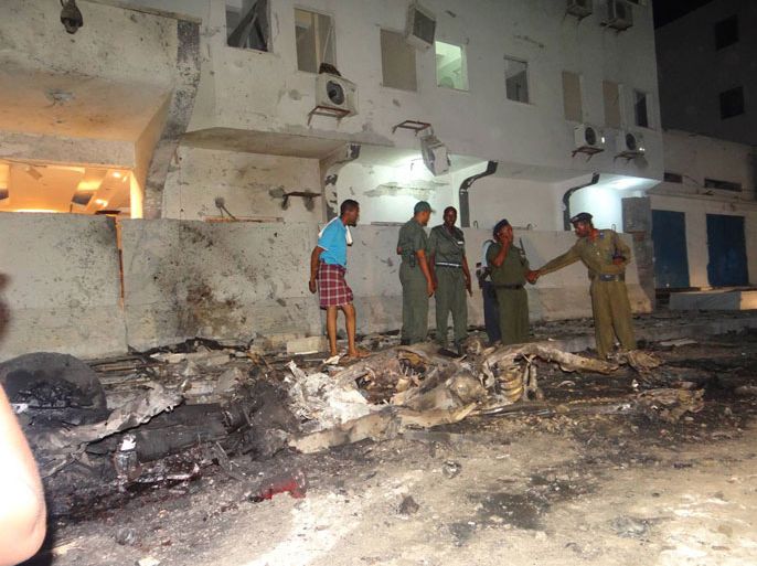ضباط من قوات الأمن الحكومية واقفون بجانب فندق مكة المكرمة وأماهم السيارة المفخخة التي انفجرت.