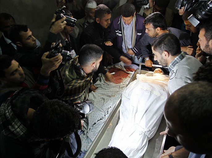 Journalists, friends and family members gather around the the body of one of four Hamas militants killed overnight in a firefight with Israeli troops at the mortuary of a hospital in Khan Younis in the southern Gaza Strip in the early hours of November 1, 2013. The local commanders of Hamas's military wing were killed by tank fire, Palestinian officials said, while the Israeli army said five of its soldiers were wounded by an explosive device. The Israeli military said the fighting erupted when an explosive device went off as troops were clearing a tunnel from the Gaza Strip into Israel, allegedly to be used as a springboard for militant attacks. AFP PHOTO / SAID KHATIB