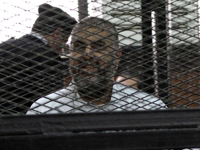 Egyptian Muslim Brotherhood senior member Khairat el-Shater smiles from inside the defendants cage during his trial in the police institute near Cairo's Turah prison on December 11, 2013. The trial of Badie and his deputies on charges related to protest deaths came to an abrupt end when the judges walked out, citing chaos in the dock. AFP PHOTO/MAHER ISKANDER