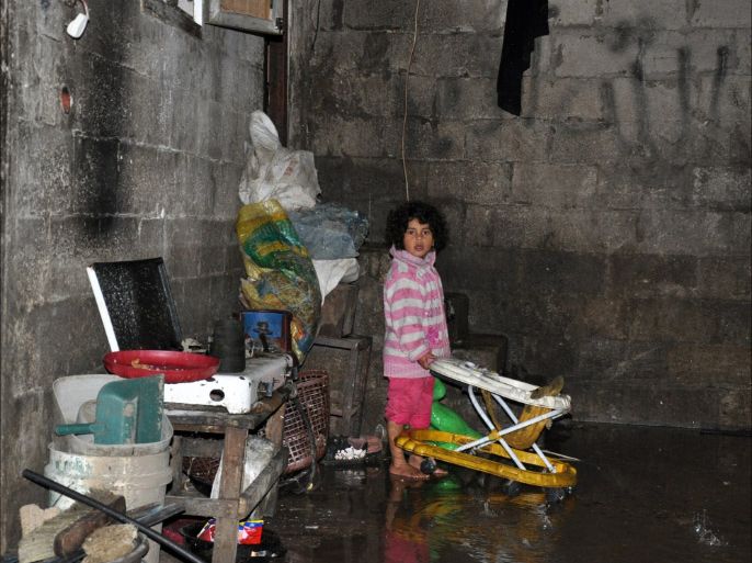 طفلة ترفع "ألعابها" من منزل عائلتها الذي غمرته مياه الأمطار