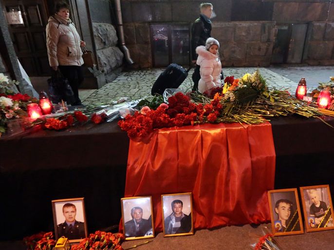 epa04004010 Passengers pass by a memorial table with portraits of victims, flowers and candles at the site of the first terrorist explosion near the main railway station in Volgograd, Russia, 30 December 2013. Reports state that at least 31 people were killed and many wounded in the bombing in the city during the last two days. EPA/MAXIM SHIPENKOV