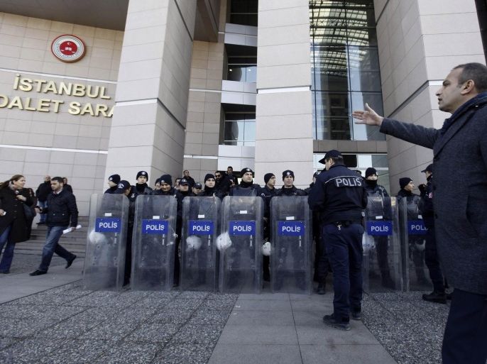 A plainclothes police officer reacts as riot police stand guard in front of the courthouse in Istanbul December 20, 2013. Turkish police arrested eight people in connection with allegations of official corruption and bribery, a newspaper said on Friday, in an investigation Prime Minister Tayyip Erdogan has called a "dirty operation" aimed at undermining his rule. REUTERS/Osman Orsal (TURKEY - Tags: POLITICS CRIME LAW)