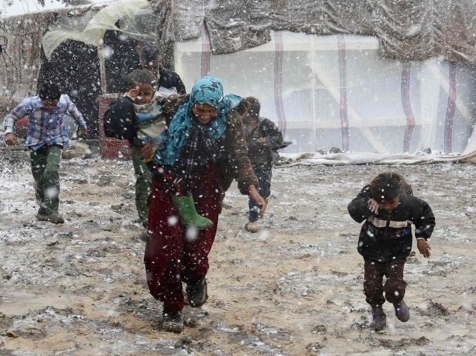 Syrian refugees run for cover from snow during a winter storm in Zahle town, in the Bekaa Valley December 11, 2013. The worst of winter is yet to come for 2.2 million refugees living outside Syria and millions more displaced inside the country. A storm named Alexa is sweeping across Syria and Lebanon, bringing with it high winds and freezing temperatures - and marking the beginning of the third winter since the Syrian conflict began in March 2011. In the tented settlement a few kilometres (miles) from the border in Lebanon's Bekaa Valley, more than 1,000 people live in rudimentary shelters. REUTERS/Mohamed Azakir (LEBANON - Tags: POLITICS CIVIL UNREST CONFLICT SOCIETY IMMIGRATION ENVIRONMENT ENERGY TPX IMAGES OF THE DAY)