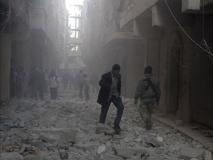 People walk on rubble at a damaged site after what activists said was an air raid by forces loyal to Syrian President Bashar Al-Assad, in Aleppo's al-Saliheen district December 23, 2013. REUTERS/Saad AboBrahim