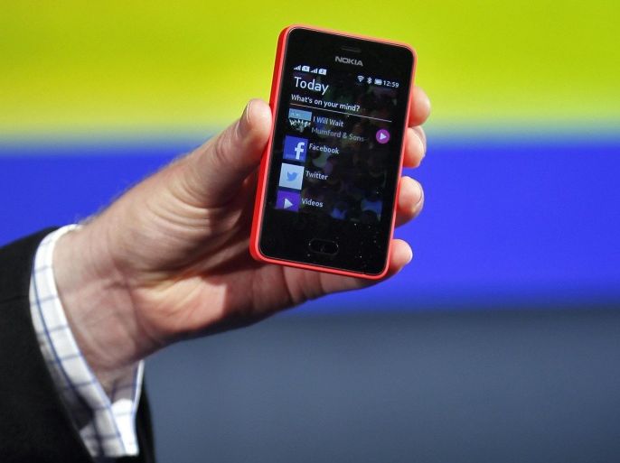 A Nokia official displays a new $99 phone in its midrange Asha line at a launch in New Delhi, in this file picture taken May 9, 2013. Microsoft Corp's acquisition of Nokia's handset business gives the software behemoth control of its main Windows smartphone partner, but leaves a question mark over the bigger business it has bought: Nokia's cheap and basic phones that still dominate emerging markets like India. To match story MICROSOFT-EMERGING/ REUTERS/Anindito Mukherjee/Files (INDIA - Tags: BUSINESS TELECOMS)