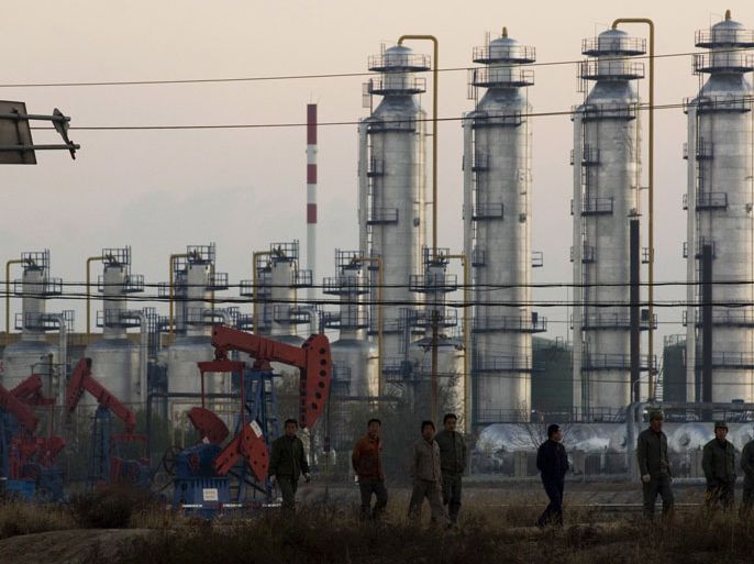 epa01169956 Oil workers pass by several oil wells and a refinery in the morning at Gudong oilfield, in suburb of Dongying city,eastern China's Shandong province, 09 November 2007. The Gudong oilfield constitutes with several other small oilfields the Shengli oilfield which belongs to the oil company SINOPEC Shengli Oilfield and is the second largest oil production base in China, ranking next to the Daqing Oilfield in northeast China. The Shengli oilfield was opened up in 1961 and development started in 1964. By the end of 2006, 74 oil or gas fields of different types had been discovered. EPA/WU HONG