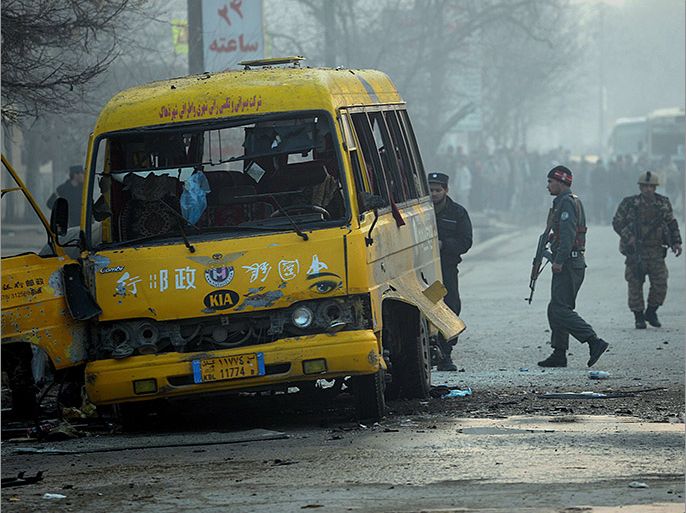 Kabul, -, AFGHANISTAN : Afghan security forces stand next to a damaged bus at the site of a suicide attack in Kabul on January 26, 2014. A Taliban suicide bomber killed at least four people in Kabul on January 26 when he targeted a Ministry of Defence bus, officials said, confirming three people in the vehicle and one female bystander had died. The attack was the first major blast in the Afghan capital since Taliban militants launched a suicide attack on January 17 against a popular restaurant killing 21 people, including 13 foreigners. "The bomber was on foot when he detonated himself next to a bus carrying Ministry of Defence staff to work," interior ministry spokesman Seddiq Seddiqi told AFP. AFP PHOTO/SHAH Marai