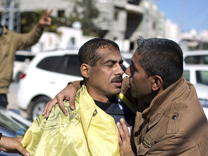 A Palestinian man (L) is hugged by a relative after he was freed from a Hamas-run jail in Gaza City, on January 8, 2014. Gaza's Hamas government freed seven members of the rival Palestinian Fatah group from its jails, in what it said was a goodwill gesture to enhance Palestinian unity and reconciliation, Hamas officials said. AFP PHOTO/MOHAMMED ABED