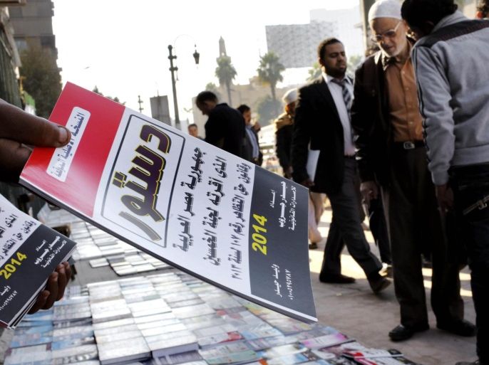 FILE - In this Saturday, Dec. 28, 2013 file photo, an Egyptian vender sells copies of the new constitution in Cairo, Egypt. With a presidential run by Egypt’s powerful military chief seeming more likely by the day, this week’s two-day constitution referendum, to be held amid a massive security force deployment, is widely seen as a vote of confidence in the regime he installed last summer. Arabic reads, "the constitution of the Arab Republic of Egypt." (AP Photo/Amr Nabil, File)