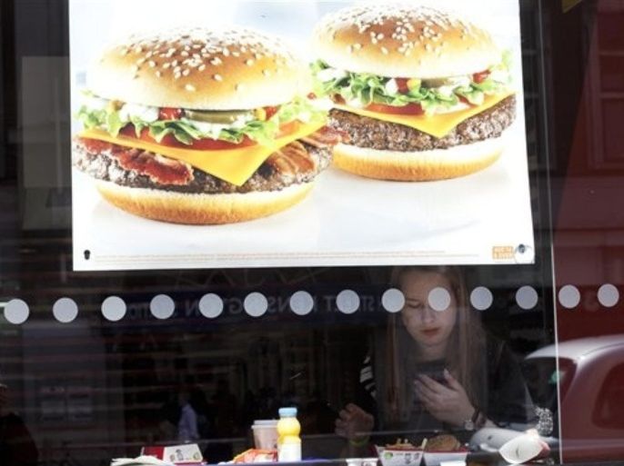 In this photo taken Monday, April 30, 2012, a woman eats her meal inside a McDonald's fast food restaurant in London. British doctors have slammed the sponsorship of the London Olympics by companies like McDonalds, saying it sends the wrong message amid the country's ballooning obesity crisis. Big Macs, fries and milkshakes will be part of McDonald's exclusive "meal brand" of the Olympics and the fast-food giant will soon be opening its largest franchise in the world, a two-storey cathedral-like restaurant that seats 1,500 customers, at London's Olympic Park.