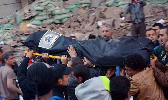 People carry a body of a man killed at the site of a bomb attack in front of Cairo Security Directorate building, which includes police and state security, in downtown Cairo, January 24, 2014. A suicide car bomber blew himself up in the parking lot of a top security compound in central Cairo on Friday, killing at least four people in one of the most high-profile attacks on the state in months, security sources said. REUTERS/Al Youm Al Saabi Newspaper (EGYPT - Tags: POLITICS CIVIL UNREST CRIME LAW) TEMPLATE OUT. EGYPT OUT. NO COMMERCIAL OR EDITORIAL SALES IN EGYPT