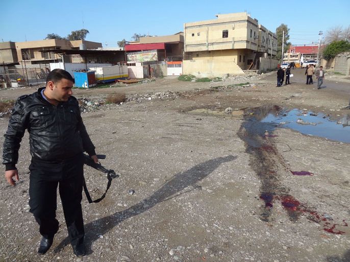 Kirkuk, -, IRAQ : A member of Iraqi security forces inspects the site of a bomb explosion in the northern Iraqi city of Kirkuk on January 18, 2014. In Baghdad, seven attacks -- including a half-dozen car bombs -- killed at least 20 people and wounded more than 60 others, security and medical officials said. AFP PHOTO / MARWAN IBRAHIM