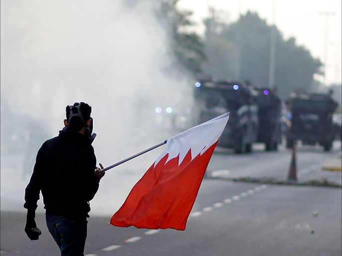 An anti-government protester holds a Bahraini flag during clashes with riot police after the funeral procession of Fadhel Abas Muslim in the village of Diraz, west of Manama, January 26, 2014.