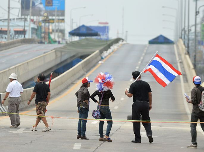 THAILAND : Anti-government demonstrators holdingThai flags stand at a road blockade at Chaeng Wattana in Bangkok on February 15, 2014. Protestors have vowed to continue their rallies a day after police tried to clear the protest sites near the government headquarters. AFP PHOTO/Manjunath KIRAN