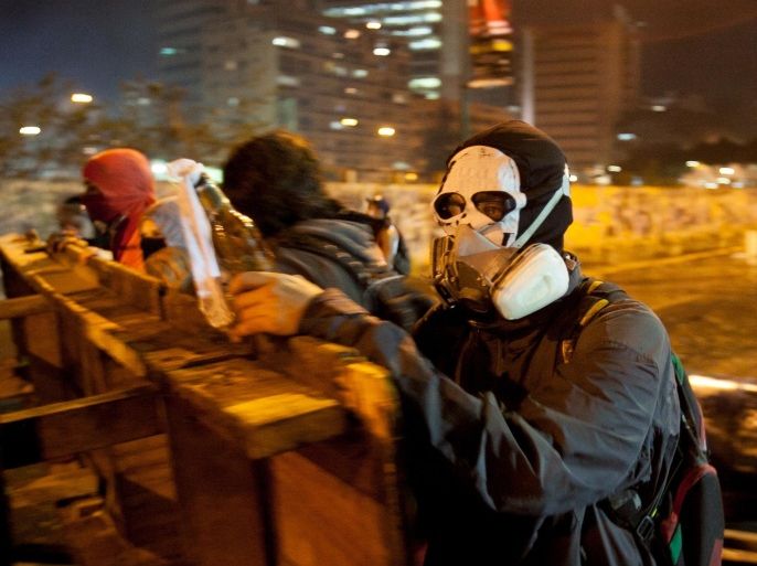 A protester wearing a painter's mask helps build a barricade against the advance of a police water cannon in the Altamira neighborhood of Caracas, Venezuela, Wednesday, Feb. 19, 2014. The opposition is protesting the Tuesday detention of thier leader Leopoldo Lopez, as well as rampant crime, shortages of consumer goods and an inflation rate of more than 50 percent. (AP Photo/Alejandro Cegarra)