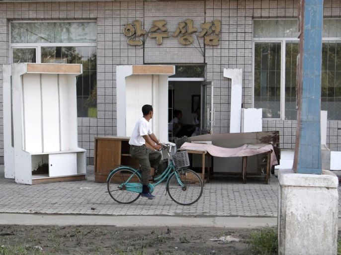 CORRECTS PROVINCE TO SOUTH PHYONGAN - In this Aug. 4, 2012 photo, a North Korean cycles past a shop where goods have been set out on the sidewalk to dry after being flooded in the city of Anju in South Phyongan Province, North Korea. A North Korean Red Cross official says that there is a chance for outbreak of diseases in the flood-stricken city due to the lack of clean water.