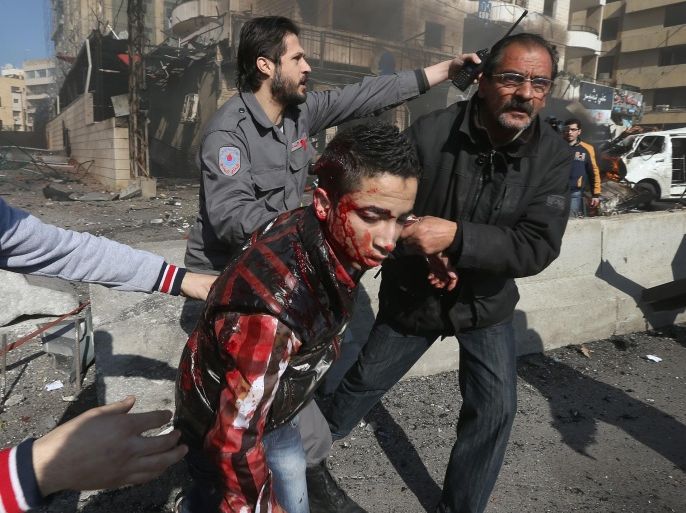 A wounded man is assisted at the site of an explosion, near the Kuwaiti Embassy and Iran's cultural center, in the suburb of Beir Hassan, Beirut, Lebanon, Wednesday, Feb. 19, 2014. A blast in a Shiite district in southern Beirut killed at least two people on Wednesday, security officials said — the latest apparent attack linked to the civil war in neighboring Syria. (AP Photo/Hussein Malla)