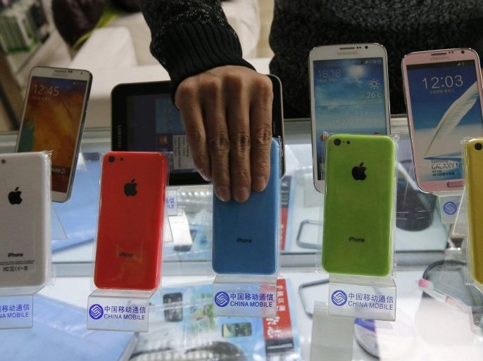 A clerk arranges Apple's iPhone 5C phones on racks bearing the logo of China Mobile, at a mobile phone shop in Beijing December 23, 2013. REUTERS/Kim Kyung-Hoon
