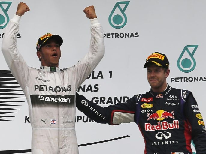 Mercedes Formula One driver Lewis Hamilton of Britain celebrates on the podium as he stands beside third-placed Red Bull Formula One driver Sebastian Vettel of Germany after the Malaysian F1 Grand Prix at Sepang International Circuit outside Kuala Lumpur, March 30, 2014. Hamilton won the Malaysian Grand Prix with a pole-to-flag victory ahead of Nico Rosberg on Sunday in a first Mercedes one-two since they returned to Formula One as a works team in 2010. REUTERS/Samsul Said (MALAYSIA - Tags: SPORT MOTORSPORT F1 TPX IMAGES OF THE DAY)