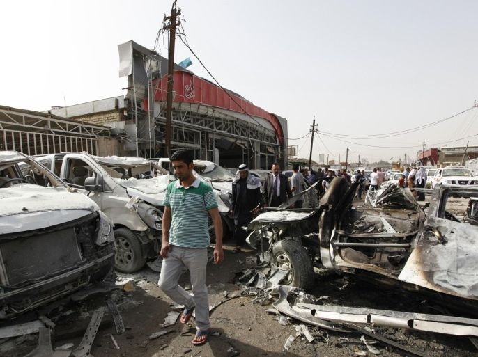 People walk past the site of a car bomb attack at car dealers' shops in Baghdad, March 7, 2014. At least 26 people were killed in Iraq on March 6, 2014 as insurgents set off roadside bombs and detonated explosives-packed cars in Baghdad and elsewhere, police said. REUTERS/Ahmed Saad (IRAQ - Tags: CIVIL UNREST POLITICS BUSINESS)