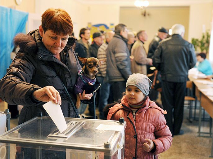 A woman casts her vote while holding her dog at a polling station on March 16, 2014 in Simferopol. Polls opened in Crimea on March 16 for a unique referendum on breaking away from Ukraine and join Russia that has precipitated a Cold War-style security crisis on Europe's eastern frontier. Ukraine's new government and most of the international community except Russia have said they will not recognise a result expected to be overwhelmingly in favour of immediate secession. AFP PHOTO / VIKTOR DRACHEV