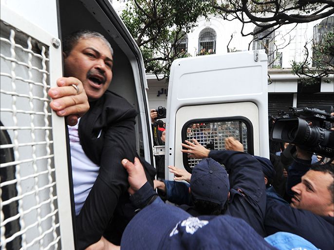 Algerian police arrest Algerian journalist Hafnaoui Ghoul (L) during a protest against Algerian President Abdelaziz Bouteflika running in the April presidential elections in Algiers on March 1, 2014. Bouteflika, who has been in power since 1999, will run for a fourth term in April, despite his health problems which are fueling doubts about his ability to lead the country. AFP PHOTO / FAROUK BATICHE