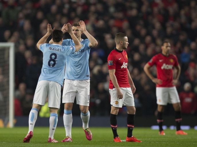 Manchester City's Edin Dzeko, second left, celebrates with teammates Samir Nasri after scoring against Manchester United during their English Premier League soccer match at Old Trafford Stadium, Manchester, England, Tuesday March 25, 2014. (AP Photo/Jon Super)