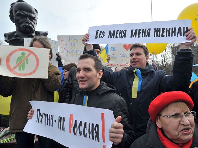 Pro-Ukrainian supporters hold flags and placards reading "Putin is not Russia" and "Crimea is Ukraine" during the rally being held to commemorate the 200th anniversary of poet and national icon Taras Shevchenko in the  Crimean city of Simferopol on March 9, 2014. AFP PHOTO/ GENYA SAVILOV