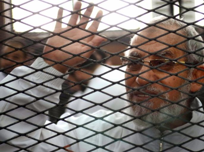 Egyptian Muslim Brotherhood's supreme guide , Mohamed Badie waves from inside the defendants cage during the trial of Brotherhood members on February 3, 2014 in the police institute near Cairo's Turah prison. The trial resumes of Mohamed Badie and more than 50 others on charges of inciting violence that left two dead in the Nile Delta city of Qaliub, after the ouster of Islamist president Mohamed Morsi. AFP PHOTO / AHMED GAMIL