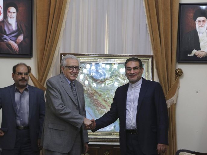 Iran's Supreme National Security Council, Ali Shamkhani, right, shakes hands with U.N.-Arab League mediator Lakhdar Brahimi under the portraits of late Iranian revolutionary founder Ayatollah Khomeini, top left, and supreme leader Ayatollah Ali Khamenei at the start of their meeting in Tehran, Iran, Sunday, March 16, 2014. Brahimi is on a trip to speak with top officials in Iran, a major backer of Syrian President Bashar Assad. An unidentified interpreter stands at left. (AP Photo/Vahid Salemi)